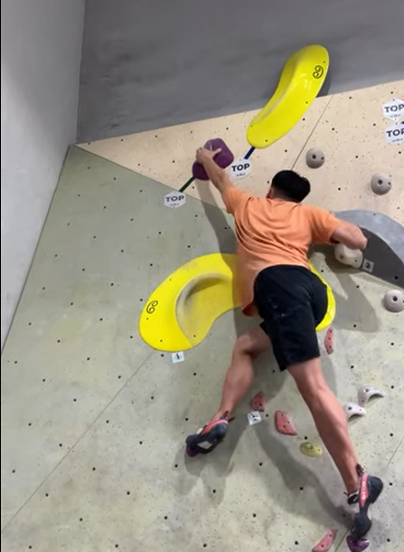 The author reaching for a hold in a bouldering gym.